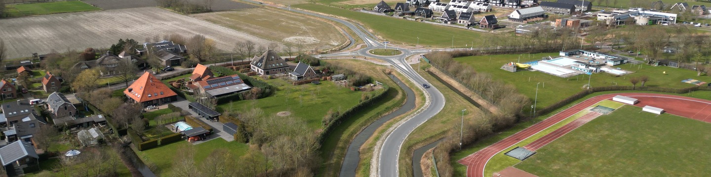 Luchtfoto van rotonde, sportveld en bebouwing